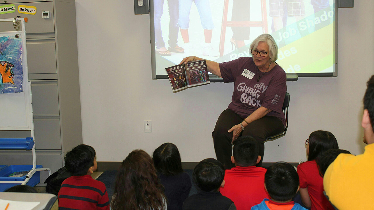 Woman reading book to class